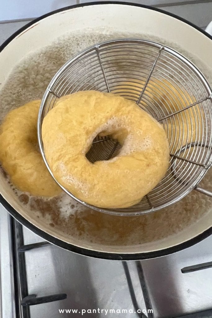 Hervir bagels de calabaza con masa fermentada en agua con miel y usar una cuchara ranurada para sacarlos del agua hirviendo.