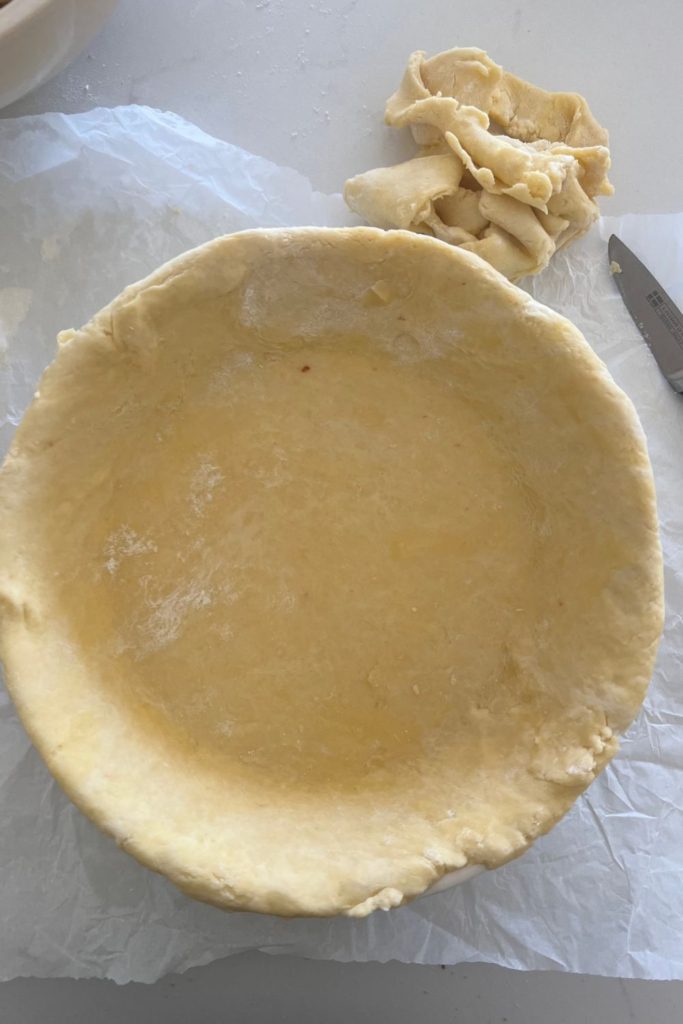 Colocar la masa de pastel de masa fermentada en un molde para pastel y cortar el exceso de corteza con un cuchillo pequeño y afilado.