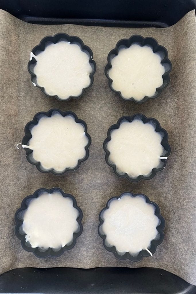 Seis porciones de base de masa fermentada colocadas en moldes de tarta de silicona listos para el congelador.
