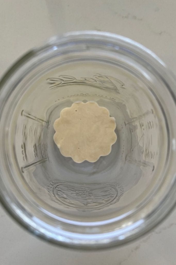 Porción de masa fermentada congelada sentada en el fondo de un frasco grande.