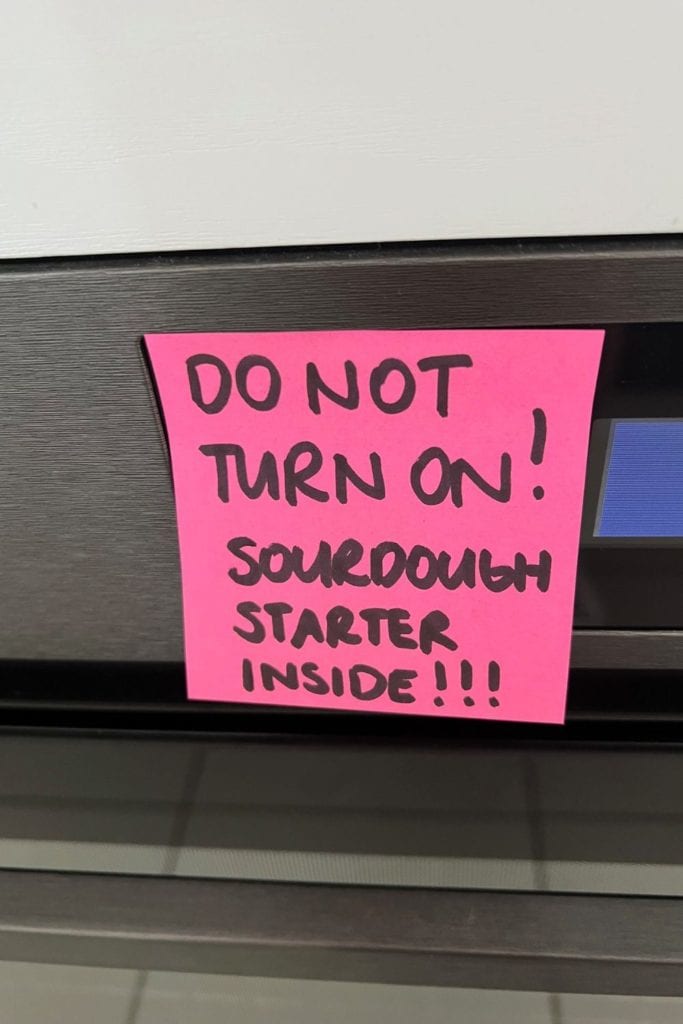 Nota rosa pegada sobre los controles del horno.  Dice "No encender - Arrancador de masa fermentada adentro"