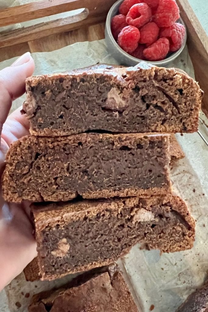 Primer plano del interior del brownie de chocolate con masa fermentada - mano sosteniendo tres rebanadas de brownie de chocolate con masa fermentada.